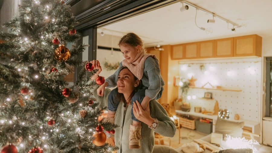 Mutter und Tochter beim Schmücken eines Weihnachtsbaumes